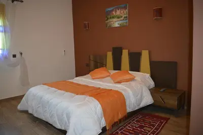 a bedroom with a bed with orange pillows on it at Maison d'hôtes Tinwitchi in Azilal