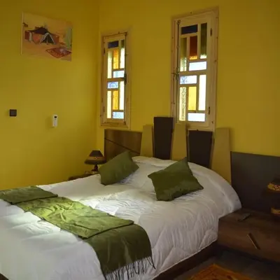 a bedroom with a large white bed with green pillows at Maison d'hôtes Tinwitchi in Azilal