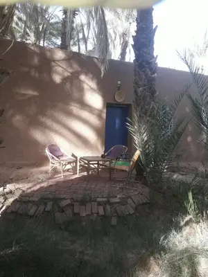 two chairs and a table in front of a house at Riad Tagmadarte Ferme d'Hôte in Zagora