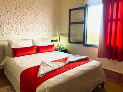 a bedroom with a bed with red pillows and a window at Hotel Kasbah Ennakhile - Authentic Stay in Nkob in Nkob
