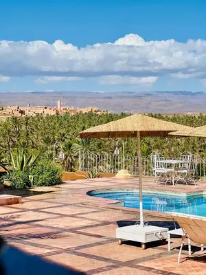 a patio with an umbrella and chairs and a pool at Hotel Kasbah Ennakhile - Authentic Stay in Nkob in Nkob