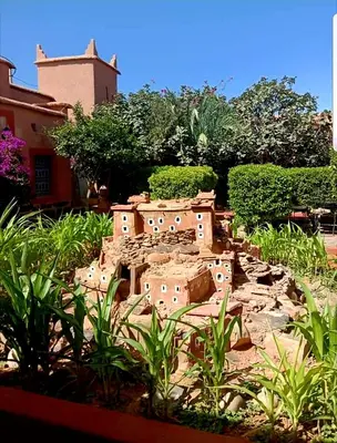 a building made out of rocks in a garden at Hotel Kasbah Ennakhile - Authentic Stay in Nkob in Nkob