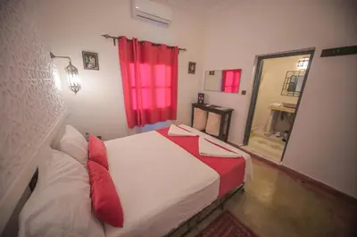 a bedroom with a bed and a red window at Hotel Kasbah Ennakhile - Authentic Stay in Nkob in Nkob