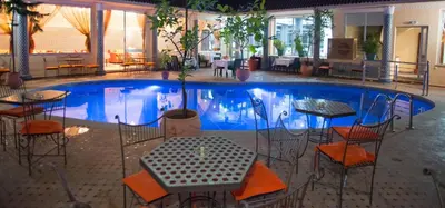 a large swimming pool with tables and chairs in front of it at Hôtel Rif in Meknès