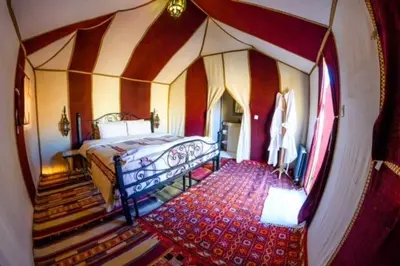 a bedroom with a bed and stairs in a room at Asama Luxury Camp in Merzouga