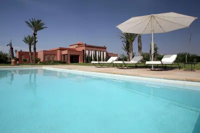 a swimming pool with two chairs and an umbrella at Dar Kamango in Marrakech