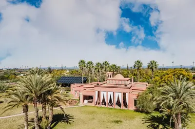 an exterior view of a pink house with palm trees at Dar Kamango in Marrakech