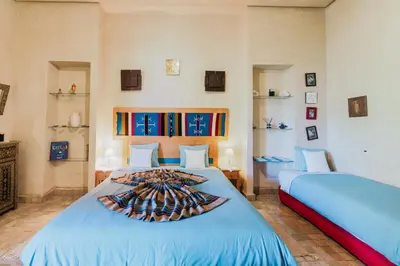 a bedroom with two beds with blue sheets and shelves at Dar Kamango in Marrakech