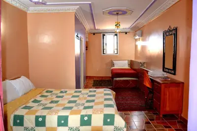 a bedroom with a bed and a dresser and a mirror at Ksar Timnay Hotel in Aguelmous
