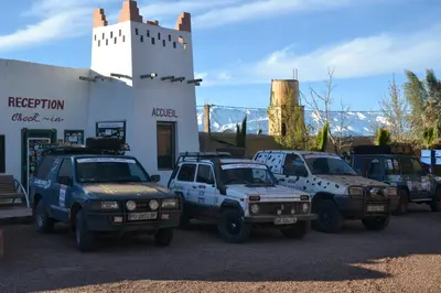 a group of trucks parked in front of a building at Ksar Timnay Hotel in Aguelmous