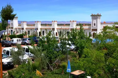 a large building with cars parked in a parking lot at Ksar Timnay Hotel in Aguelmous