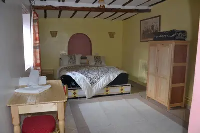 a bedroom with a bed and a wooden table at Ksar Timnay Hotel in Aguelmous