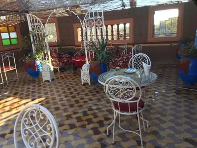 a room with white chairs and tables and plants at Karim Sahara in Zagora
