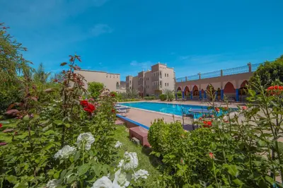 a swimming pool with flowers in front of a building at Ksar Ben Youssef in Ouarzazate