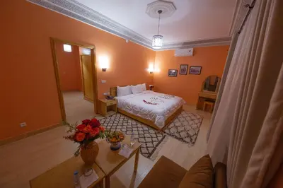 a bedroom with a bed and a table with flowers at Ksar Ben Youssef in Ouarzazate