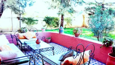 a patio with a table and chairs and a wall at Riad Dar Zidane in Meknès