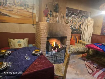 a living room with a fireplace and a table with food at Kasbah du Peintre in Aït Ben Haddou