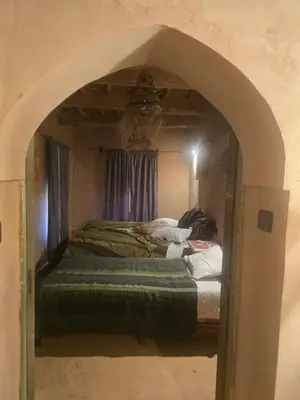 a bedroom with an archway with two beds in it at Kasbah du Peintre in Aït Ben Haddou
