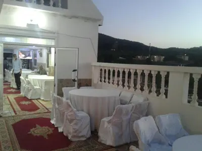 a room with a table and chairs on a balcony at Hotel Ain Leuh in Aïn Leuh