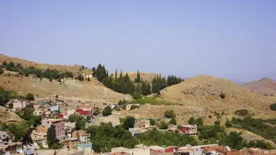 a small town on a hill with trees and houses at Hotel Ain Leuh in Aïn Leuh