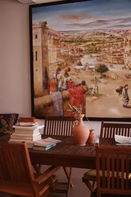 a wooden table with books and a painting on the wall at Monkey Fingers House by Fatima mellal in Tinerhir