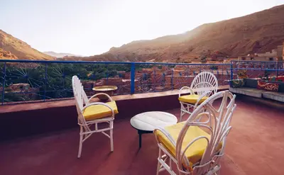 a balcony with three chairs and a table and a couch at Monkey Fingers House by Fatima mellal in Tinerhir