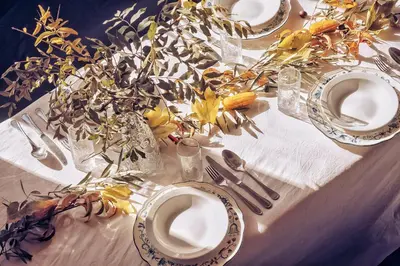 a table with plates and vases with flowers on it at Monkey Fingers House by Fatima mellal in Tinerhir