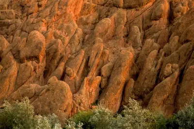 a rock wall with lots of different colored rocks at Monkey Fingers House by Fatima mellal in Tinerhir