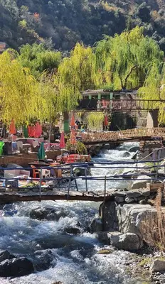 a bridge over a river with tables and chairs at Top Ourika in Aghbalou