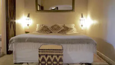 a bedroom with a large white bed with two lights at Les Jardins de Skoura in Skoura