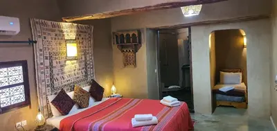 a bedroom with a red bed with towels on it at Les Jardins de Skoura in Skoura