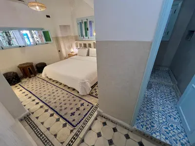 a bedroom with a bed and a tiled floor at Maison d'hôtes Dar Farhana in Ouarzazate