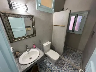 a bathroom with a sink and a toilet and a mirror at Maison d'hôtes Dar Farhana in Ouarzazate