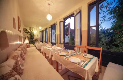 a row of tables in a restaurant with windows at Maison d'hôtes Dar Farhana in Ouarzazate