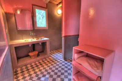 a bathroom with red walls and a checkered floor at Jardin de la source in Aït Yous