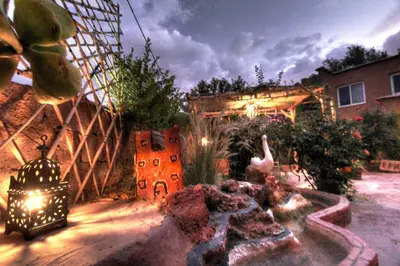 a backyard with a garden with a fountain and a building at Jardin de la source in Aït Yous