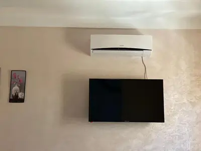 a tv on a wall with a white heater at AMAZIGH ouargaga APARTMENT in Meknès