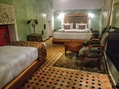 a bedroom with two beds and a table and chairs at Riad Mama H&K in Meknès