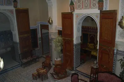 a room with a fireplace and some chairs and tables at Riad Mama H&K in Meknès
