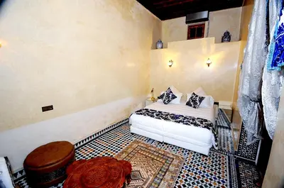 a bedroom with a white bed with pillows on it at Riad Mama H&K in Meknès