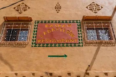 a sign on the side of a building with a green arrow at Kasbah La Datte D'or in Skoura