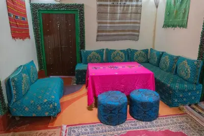 a living room with a pink table and blue chairs at Kasbah La Datte D'or in Skoura