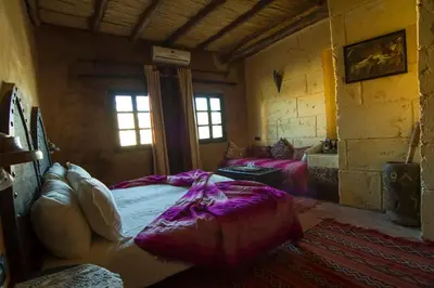 a bedroom with a bed in a room with windows at Rose Noire in Ouarzazate
