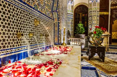 a fountain in a room with red flowers on the floor at Riad Rcif & Spa Originale in Fès