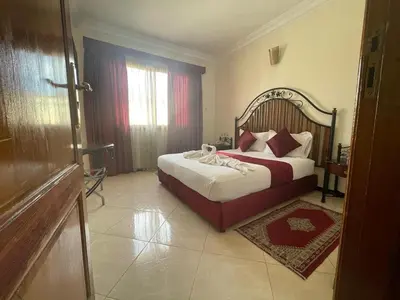 a bedroom with a large bed with red and white pillows at Perla Hôtel in Fès