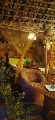 a room with wicker chairs and a table with plants at Atlas Room in Midelt