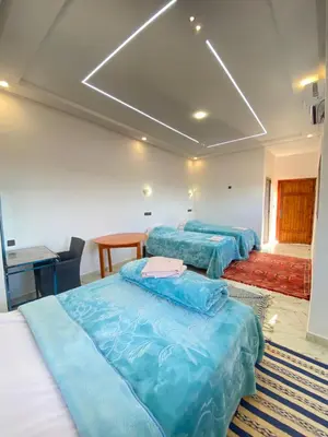 a room with three beds with blue sheets at Auberge Famille Benmoro in Skoura