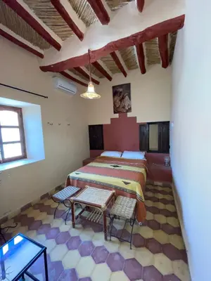 a bedroom with a bed and a table in a room at Auberge Famille Benmoro in Skoura