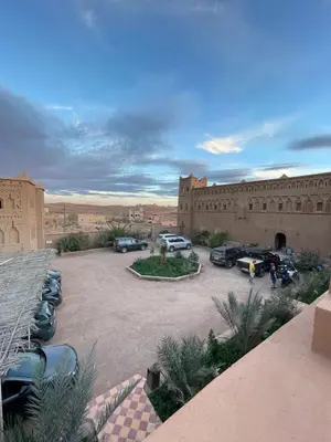 a parking lot with cars parked in front of a building at Auberge Famille Benmoro in Skoura