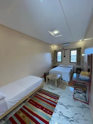 a room with two beds and a table at Auberge Famille Benmoro in Skoura